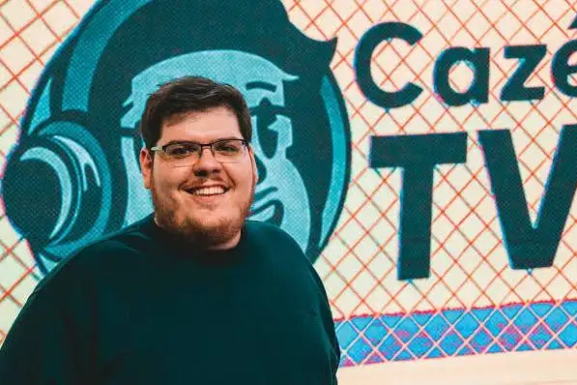 El streamer brasileño Casimiro Miguel delante del logo de Cazé TV.
